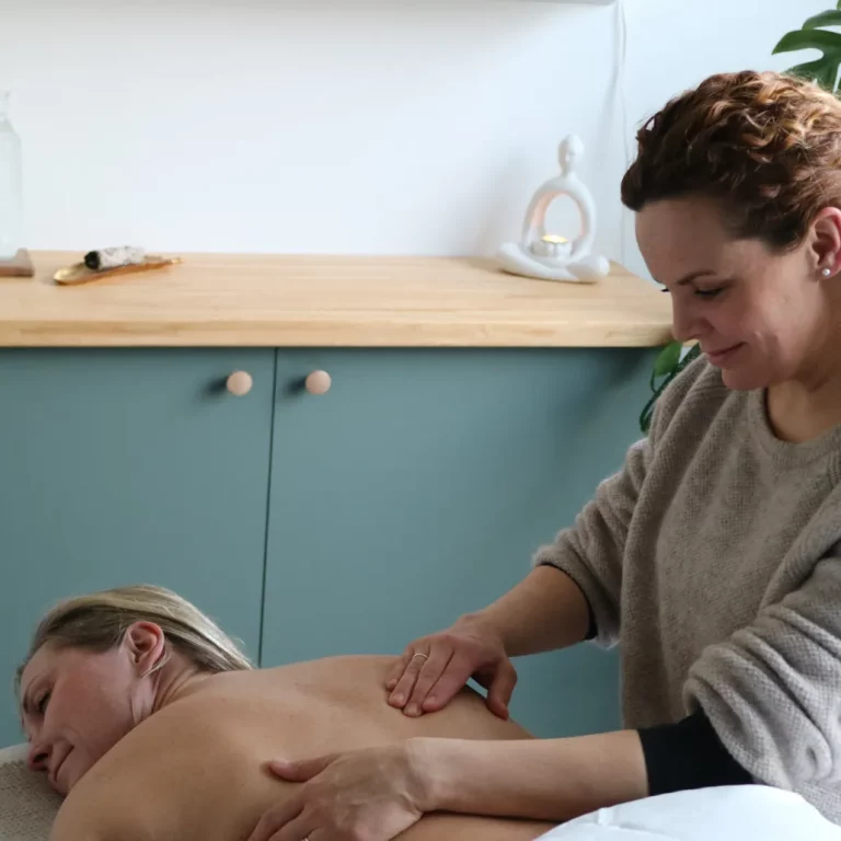 Monica, som är rosenterapeut sitter bredvid patienten som ligger på mage. Hon håller sina två händer på patientens rygg.